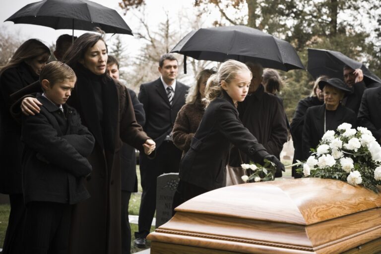 persone vestite di nero, con ombrello, a un funerale