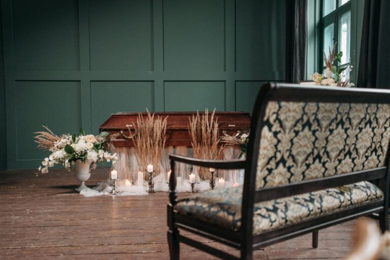 panca decorata, bara e fiori dentro una sala con pareti verdi e parquet