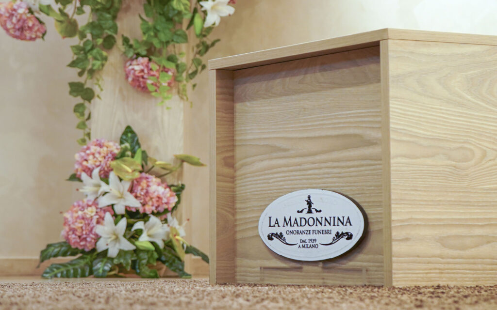 Fiori accanto a logo onoranze funebri La Madonnina Milano